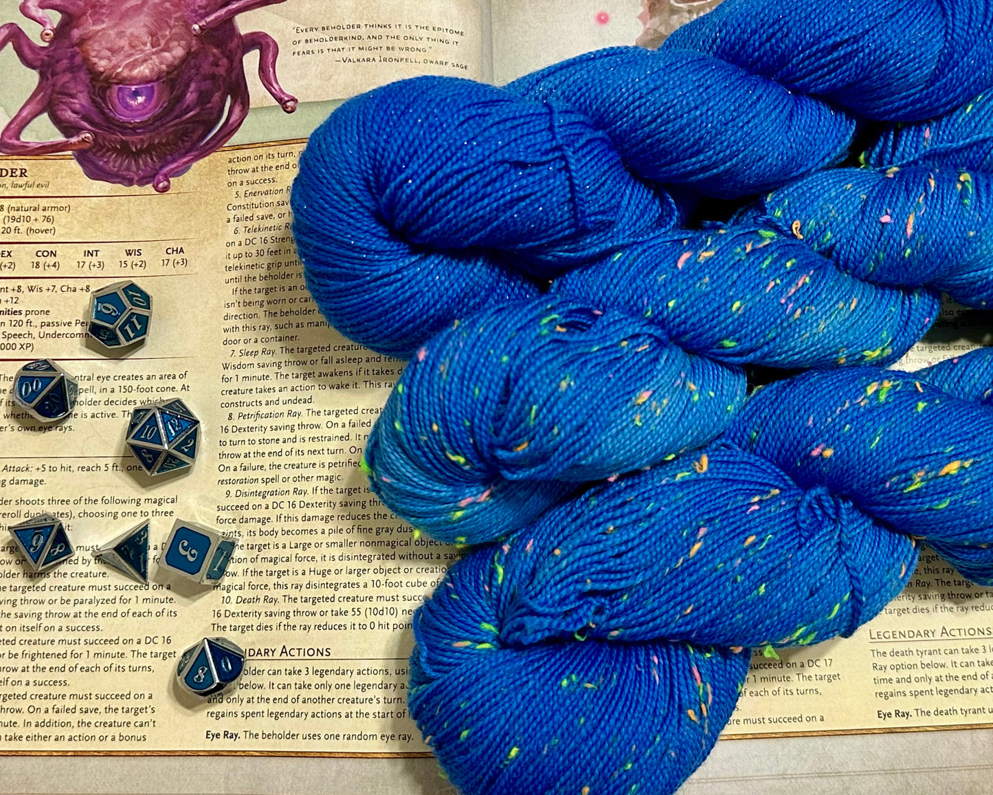 Blue yarn with speckles on a book with dice and an octopus illustration